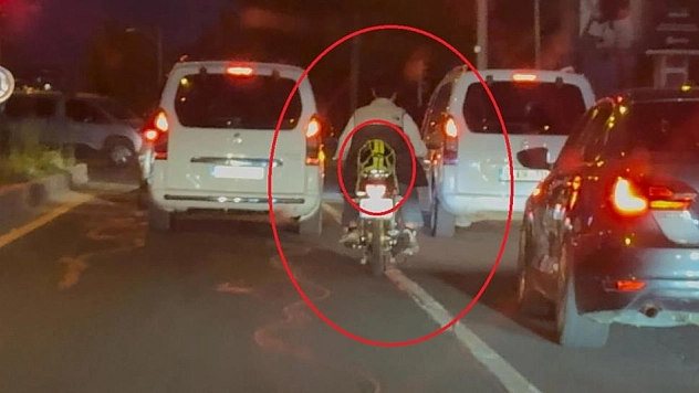 Motosiklet sürücüsü kaskı başına takmak yerine arkasına bağladı